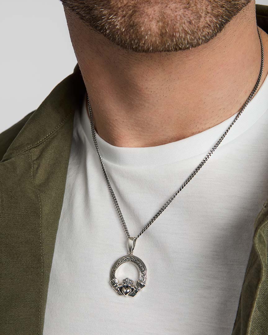 closeup image of men's silver Celtic Claddagh necklace on a model