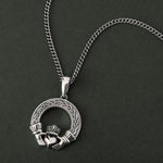 lifestyle image of mens celtic claddagh pendant with a heavy chain on a dark background 