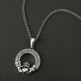 lifestyle image of mens celtic claddagh pendant with a heavy chain on a dark background 