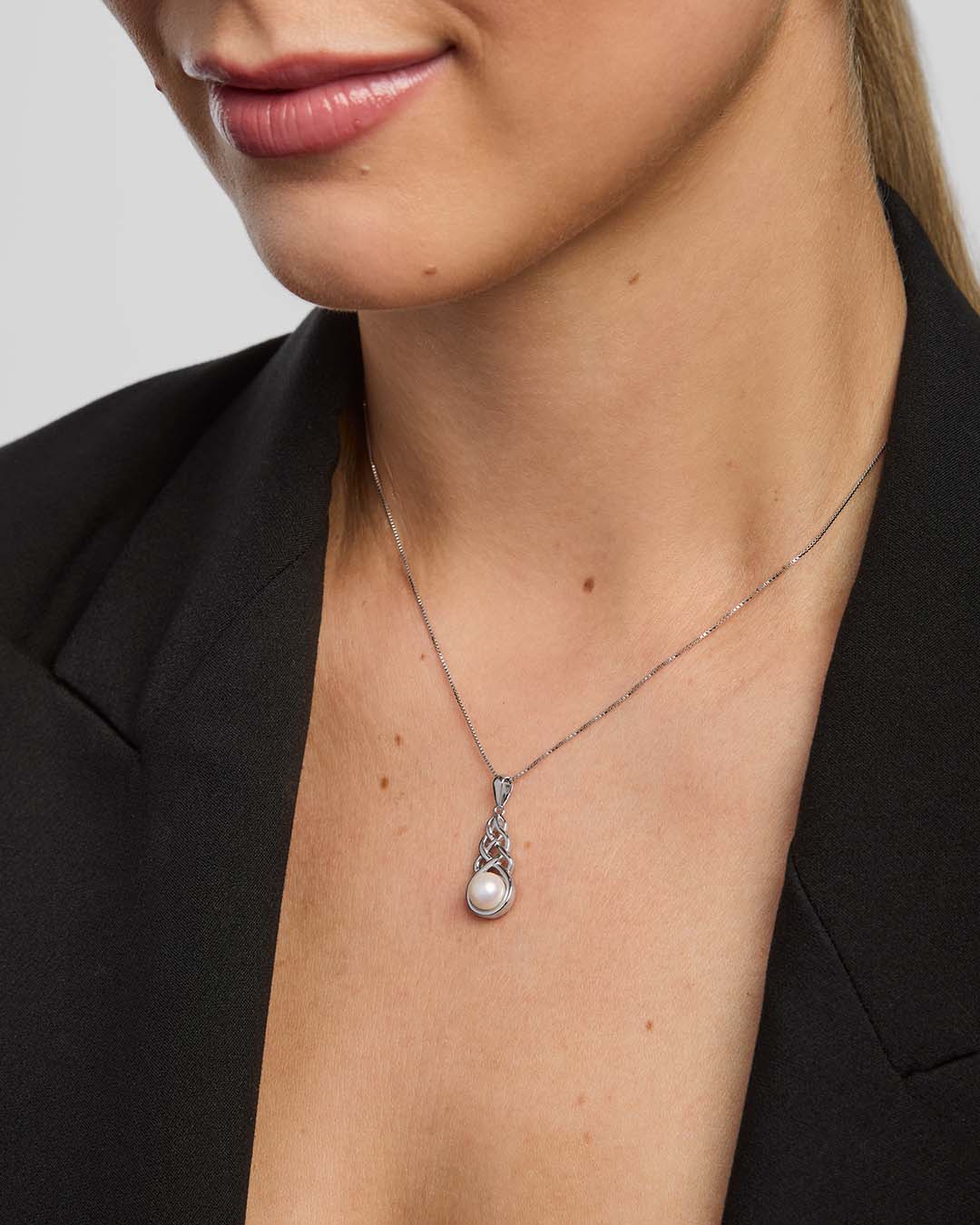 close-up image of a woman wearing Celtic knot necklace with a large round freshwater pearl in the centre