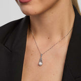 close-up image of a woman wearing Celtic knot necklace with a large round freshwater pearl in the centre