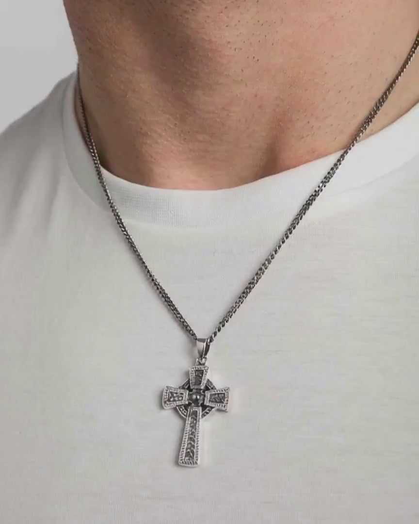 close-up video of a heavy celtic cross pendant on a male model in a white t-shirt