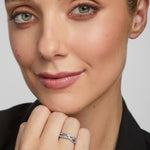 Close-up of a woman wearing a silver Claddagh ring on a plain background