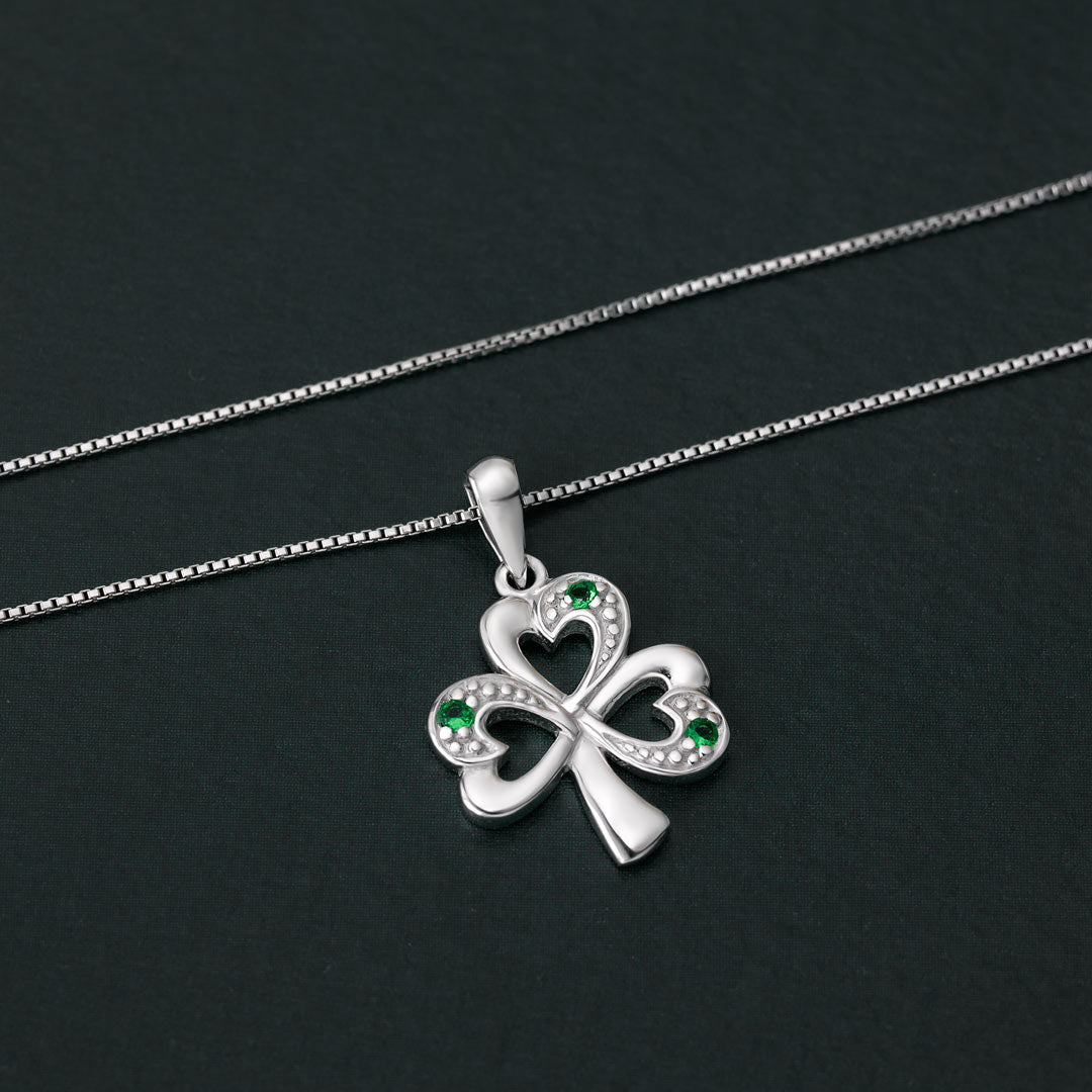 lifestyle image of Solvar silver shamrock pendant with green stones on a dark background