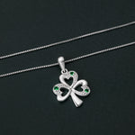 lifestyle image of Solvar silver shamrock pendant with green stones on a dark background