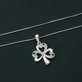 lifestyle image of Solvar silver shamrock pendant with green stones on a dark background