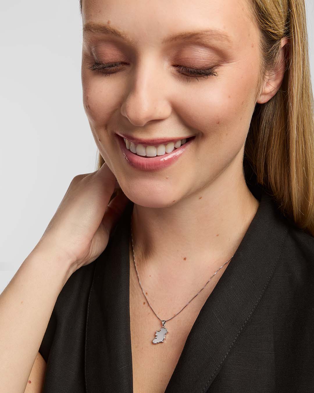A female model wearing a Solvar map of Ireland necklace pendant, centred on the chest