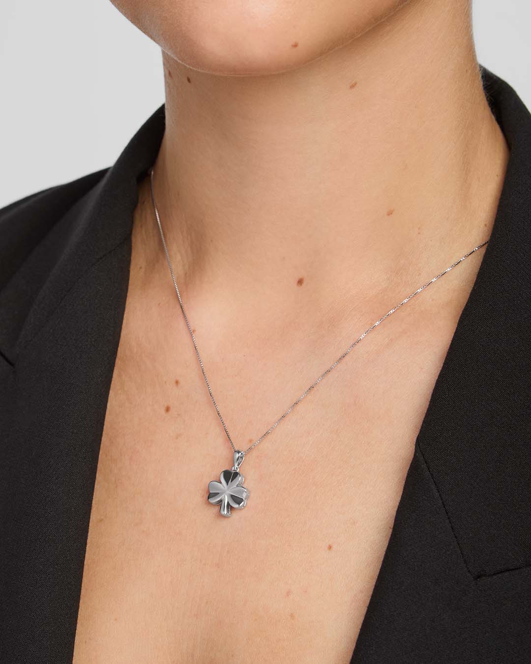 close-up image of  a female model wearing shiny silver Shamrock pendant 