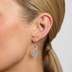 a close-up image of celtic spiral drop earrings on a model