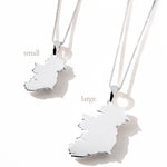 Two silver Ireland map pendant necklaces in small and large sizes, displayed side-by-side on a white surface with soft shadows
