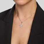 Person wearing a silver St Brigid's cross necklace against a neutral background