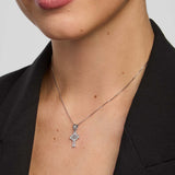 Close-up of a person wearing a small celtic cross necklace against a plain background