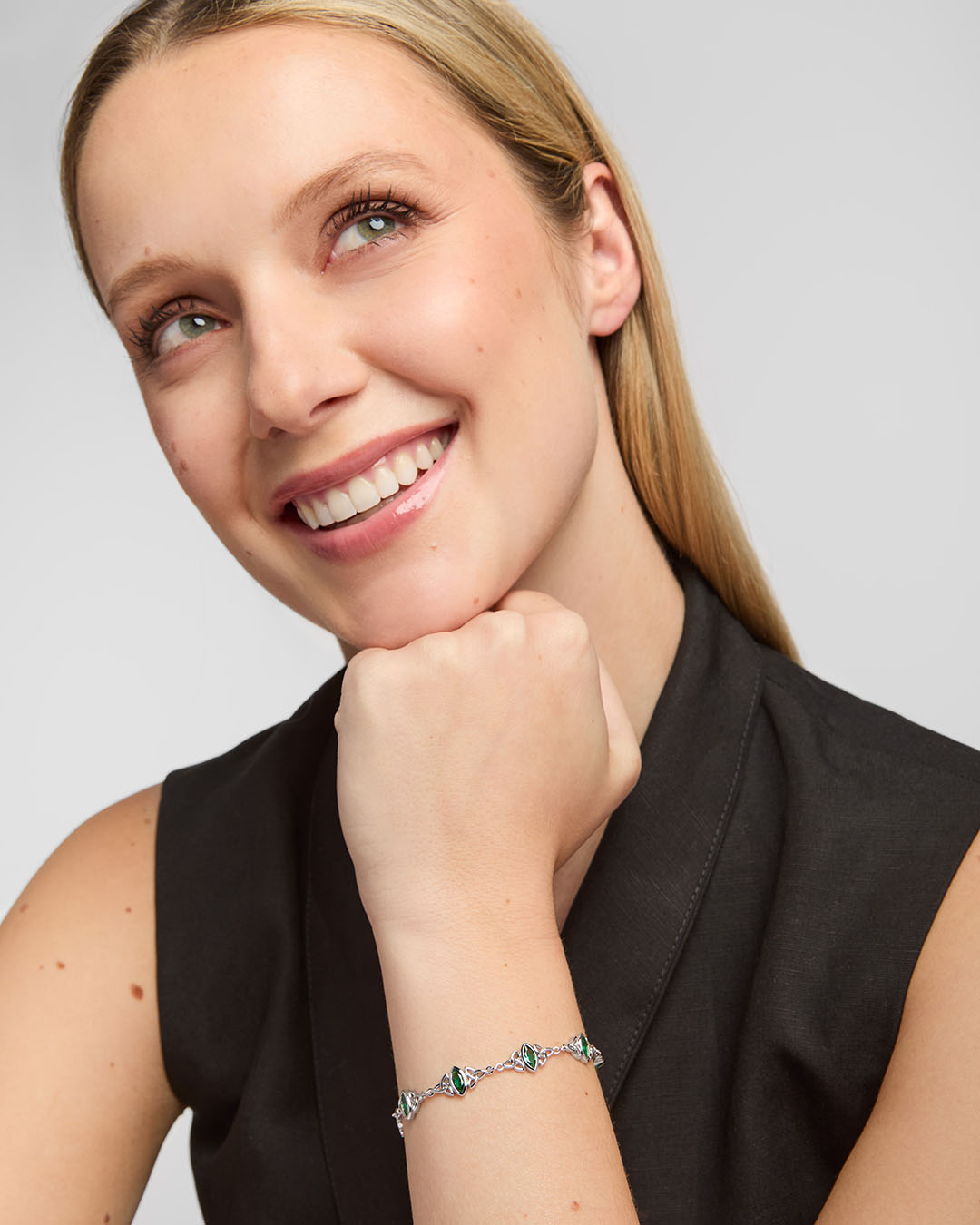 lifestyle image of a female model wearing green cubic zirconia trinity knot bracelet from Solvar