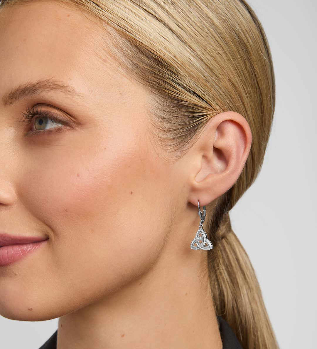 close-up image of a model wearing cubic zirconia Trinity Knot drop earrings from Solvar