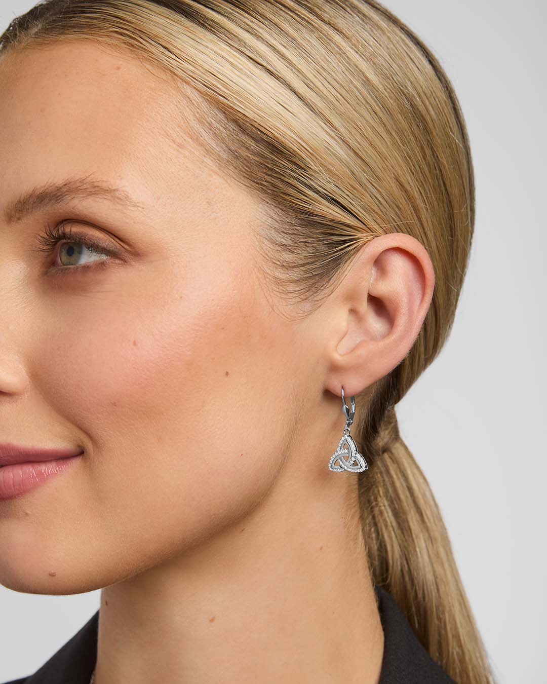 close-up image of a model wearing cubic zirconia Trinity Knot drop earrings from Solvar