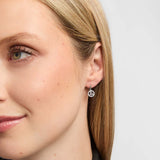 A close-up side profile of a woman wearing a small silver hoop earring with a Trinity Knot centre surrounded by sparkling clear stones.